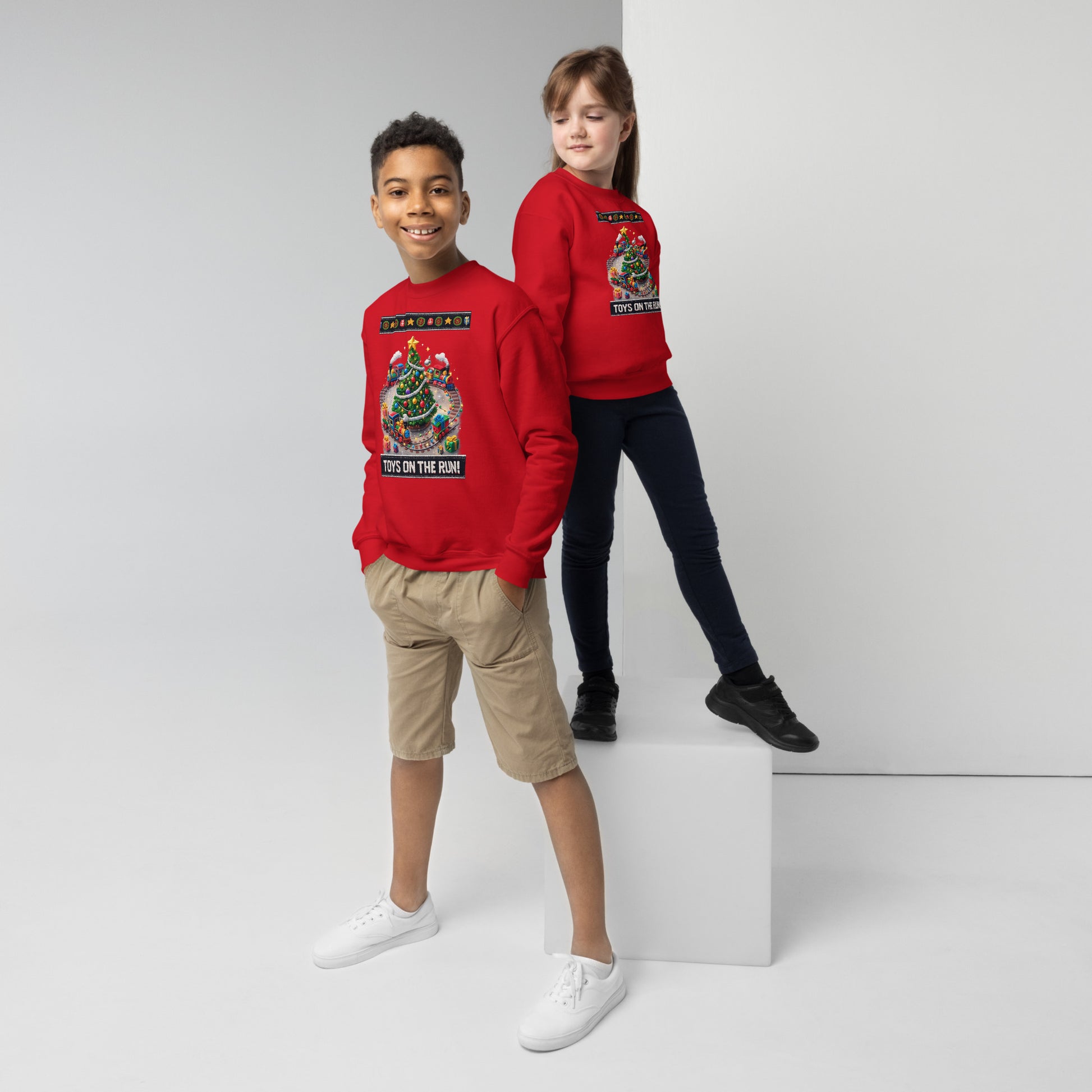 Two children wearing red sweatshirts with graphic designs on a white background