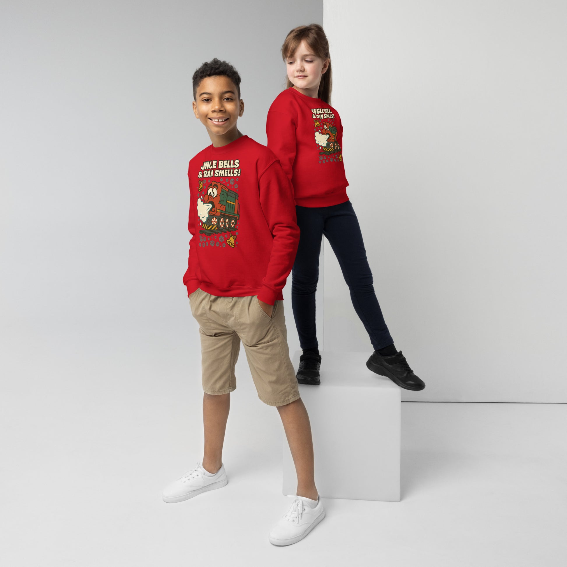 Two children wearing red Christmas-themed sweaters on a white background