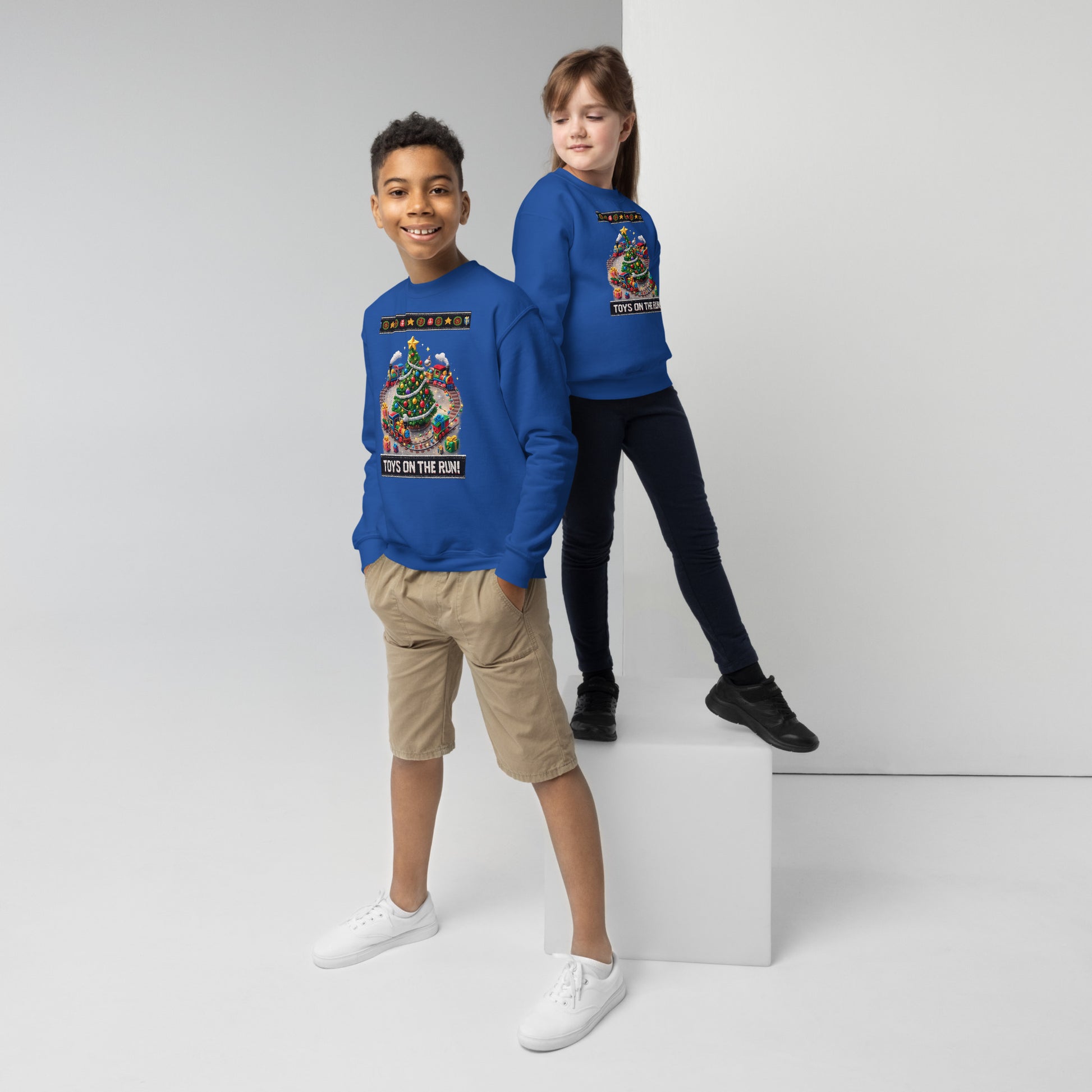 Two children wearing blue sweatshirts with colorful graphics on a white background