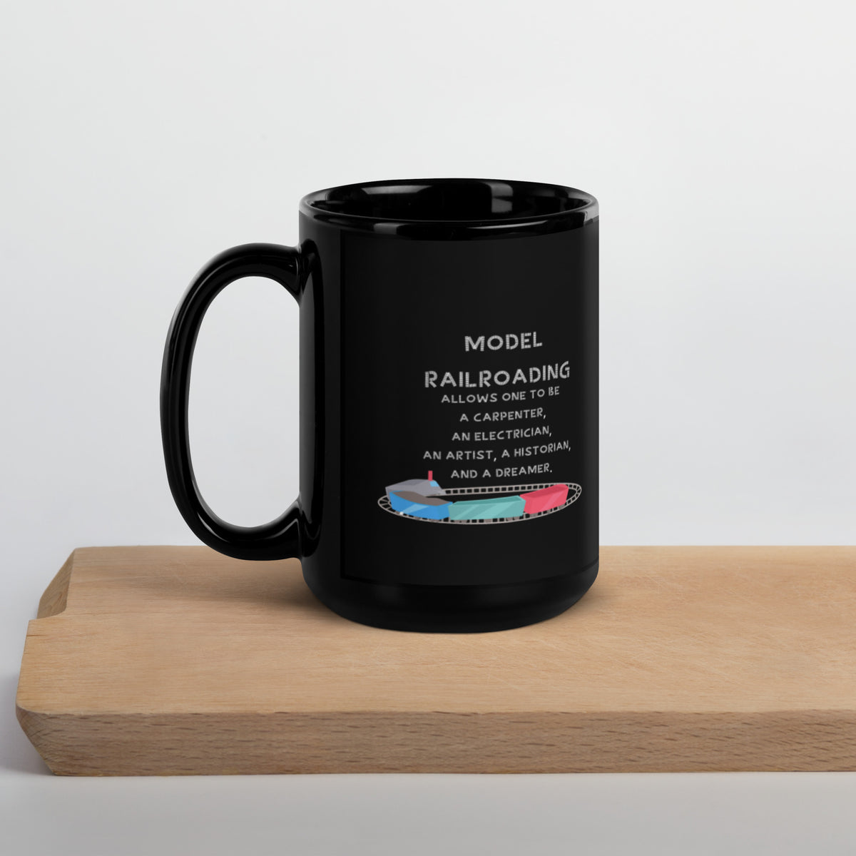 Glossy black 15 oz Model Railroading quote mug on a wooden board, handle left